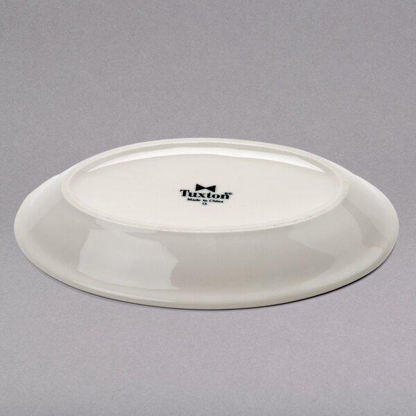 A white Tuxton oval china platter with a black rim.