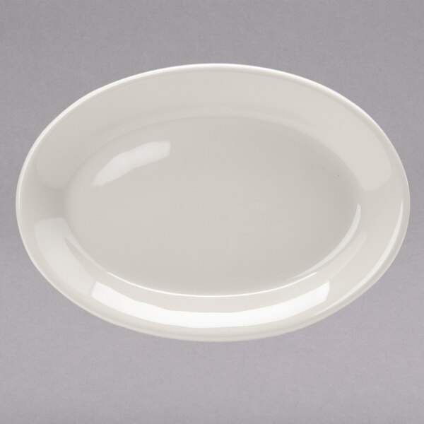 A white Tuxton oval china platter with a wide rim on a gray surface.