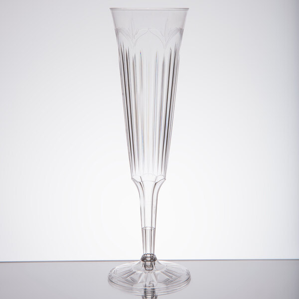 A clear plastic champagne flute with a long stem and a small design.