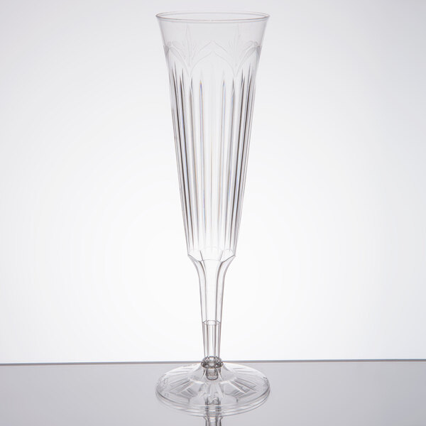 A clear plastic champagne flute with a long stem.
