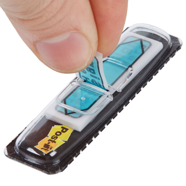 A hand holding a white piece of paper with a blue Post-it flag on it.