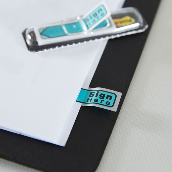 A close up of a folder with 3M Post-it "Sign Here" flags in assorted colors.
