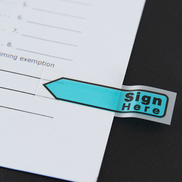 A white paper with "Sign Here" in blue and a blue arrow.