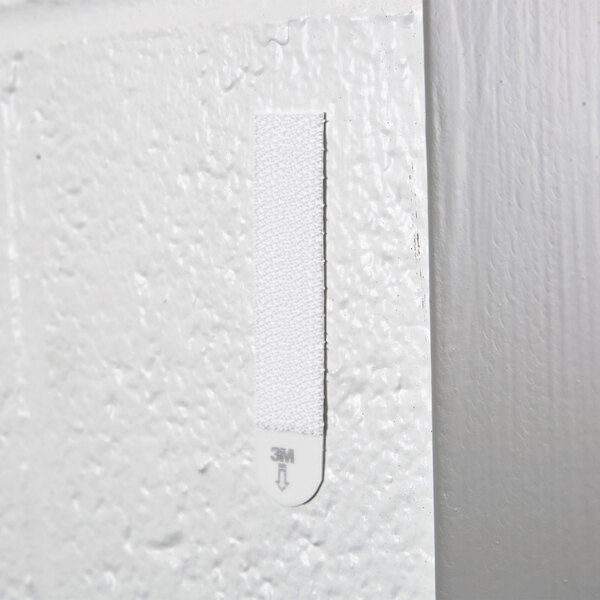 A white surface with a white Command picture hanging strip on it.