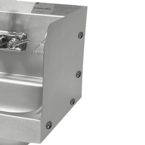 A stainless steel hand sink splash guard over a hand sink.