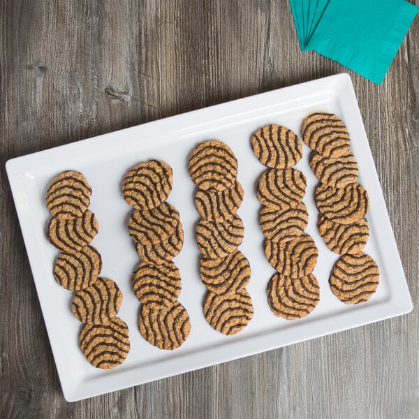 A white Elite Global Solutions rectangular melamine serving platter with a plate of cookies on it.