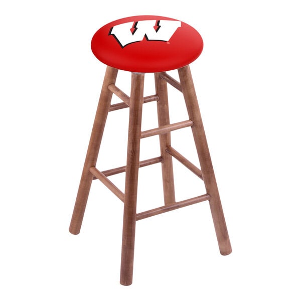 A backless wood bar stool with a red seat and a white "W" on it.