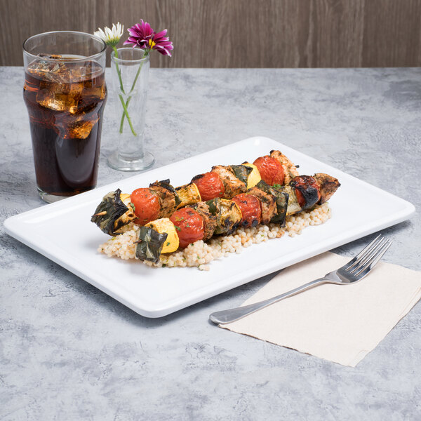 A rectangular white melamine serving platter with food and a drink on a table.