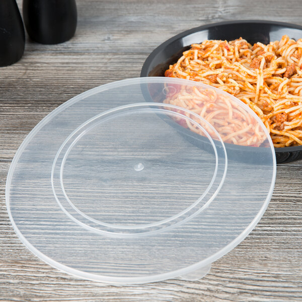 A Fineline clear plastic lid on a bowl of spaghetti with sauce.