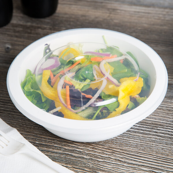 A bowl of salad with vegetables in a Fineline clear plastic bowl with a clear plastic lid.