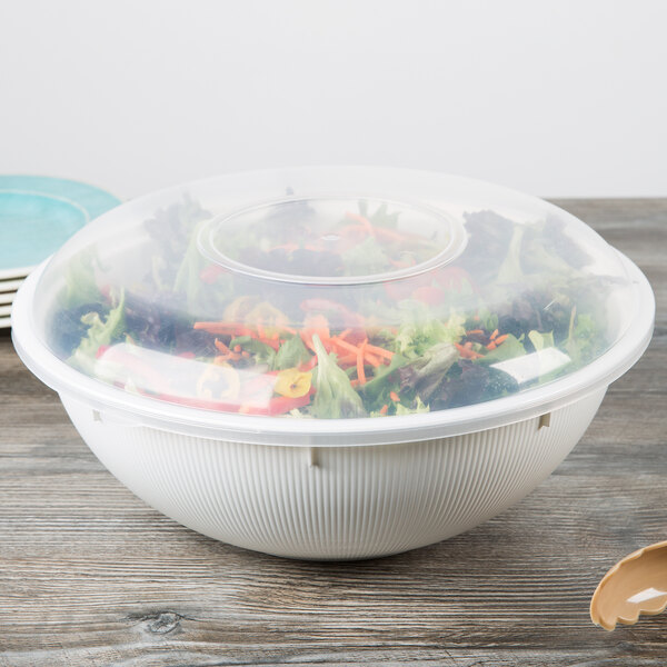A clear Fineline plastic catering bowl lid on a clear bowl filled with salad.