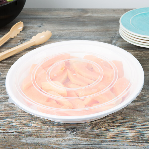 A white Fineline low profile plastic catering bowl with a spoon in it containing sliced carrots.
