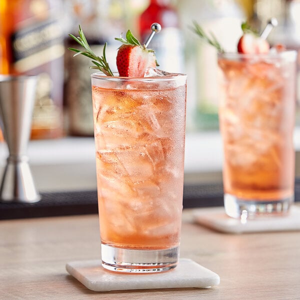 Two Acopa Straight Up beverage glasses on a table with strawberry and rosemary cocktails.