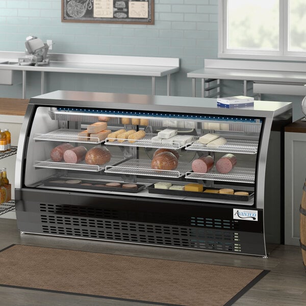 An Avantco black curved glass refrigerated deli case full of meat and cheese on a counter.