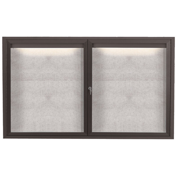 A bronze Aarco enclosed bulletin board with two glass doors and a lighted panel.