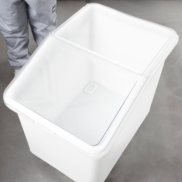 A person opening a white plastic container with a clear lid.