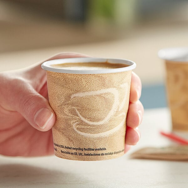 A hand holding a Solo Mistique paper hot cup of coffee with a lid.