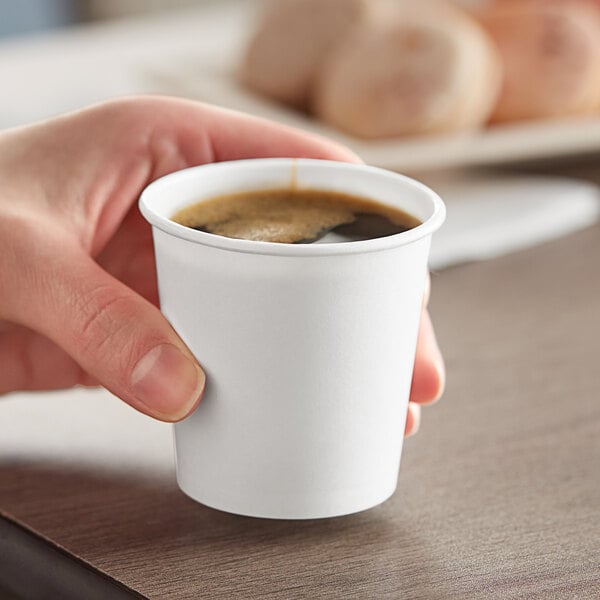 A hand holding a Solo white paper hot cup of coffee.