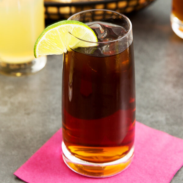 A Stolzle tumbler of brown liquid with a lime wedge on top of it.