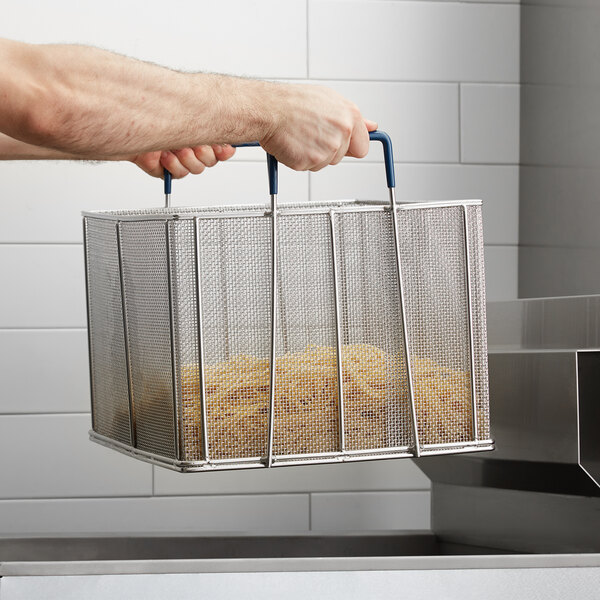 A person holding a stainless steel mesh pasta basket full of food.