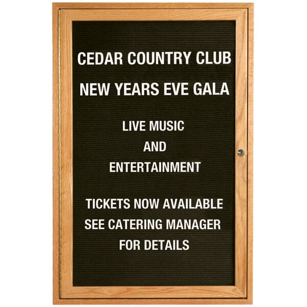 An Aarco red oak enclosed message center with a black letter board displaying white text reading "Cedar County Country Club New Year's Eve Gala" on a table at a catering event.