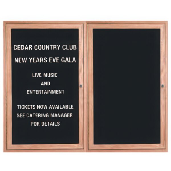 A red oak Aarco enclosed message center with black letter board and two black wooden doors with white text inside.