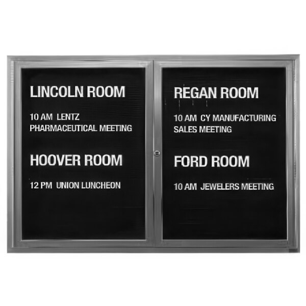 A black Aarco message center with white letters on two hinged doors.