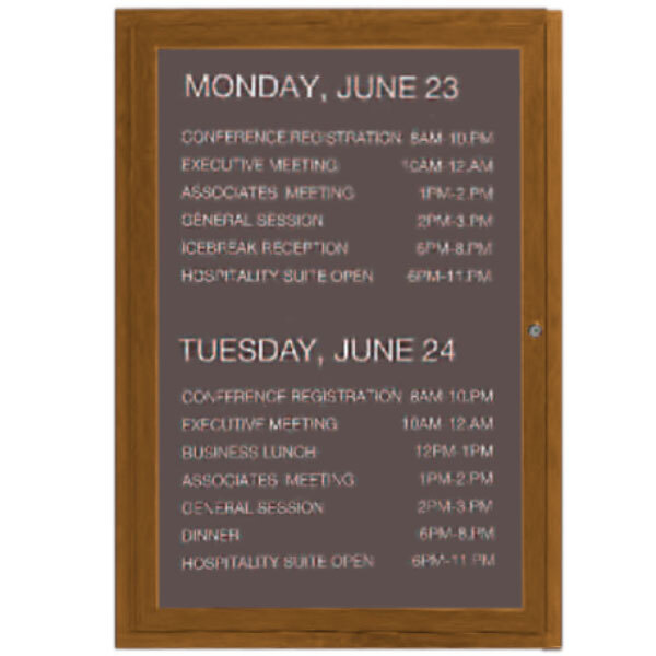 An Aarco enclosed outdoor directory board with a brown oak finish and white vinyl lettering on a schedule.