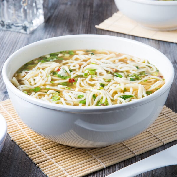 A bowl of soup with noodles served in a white Thunder Group Pho Noodle Bowl.