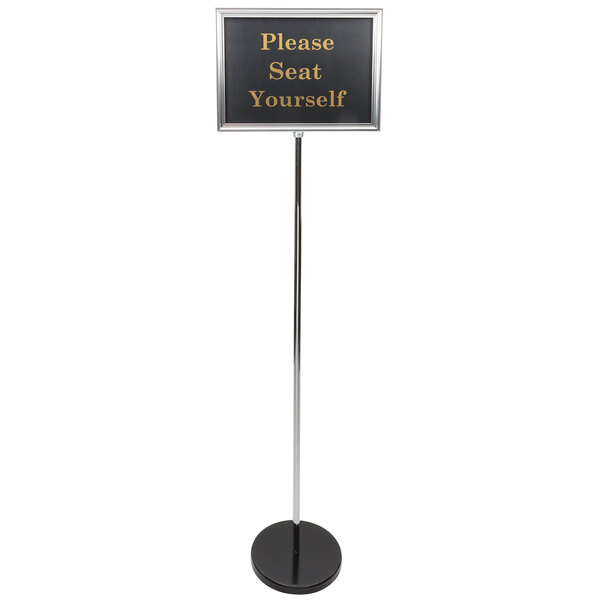 A long silver pole with a white sign on a black stand.