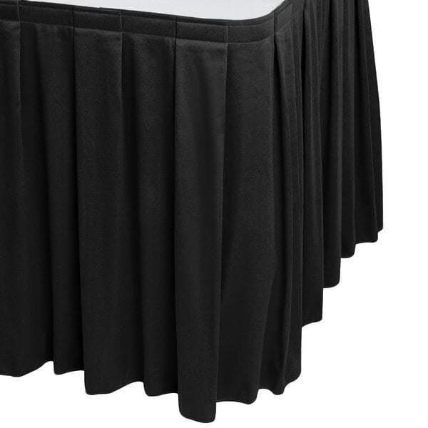 A black Snap Drape table skirt on a table with a white surface.