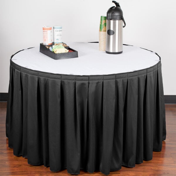 A table with a black table skirt and a tray of food on it.