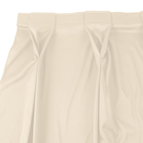 A white Snap Drape Wyndham table skirt with a pleated bow tie pattern.