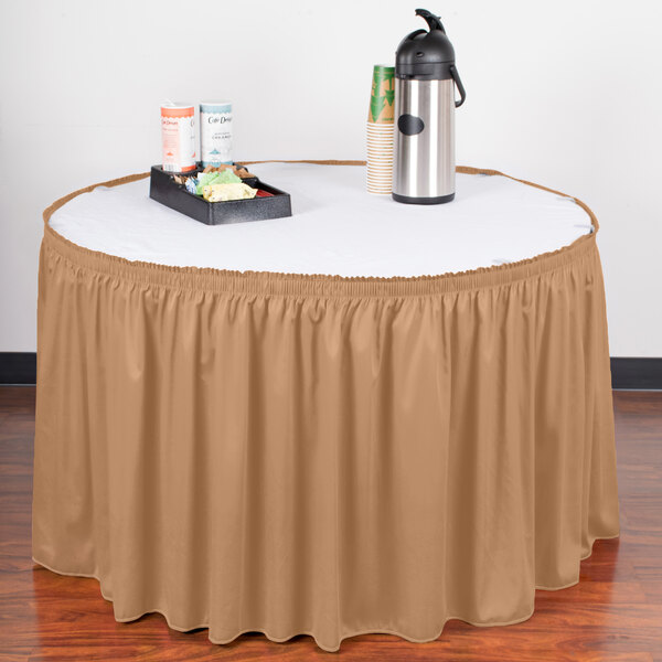 A table with a Snap Drape Wyndham Sandalwood shirred pleat table skirt on it and a tray of food.