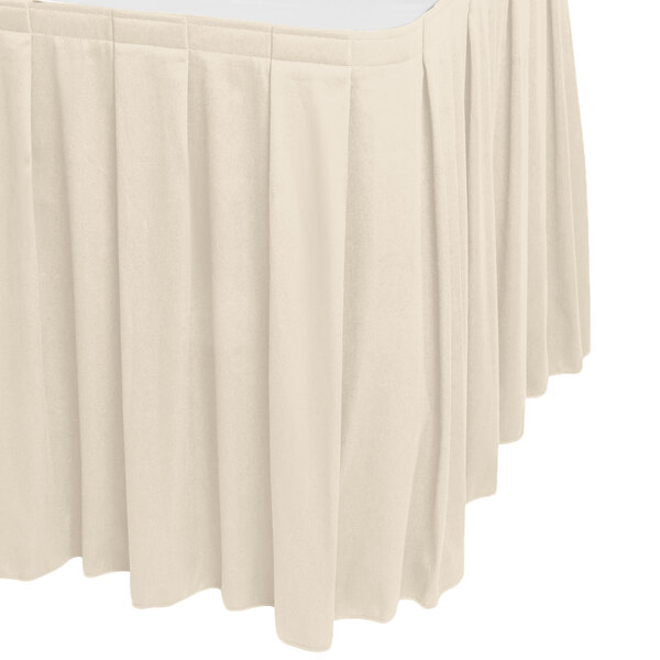A bone colored Snap Drape box pleat table skirt with Velcro clips on a table.