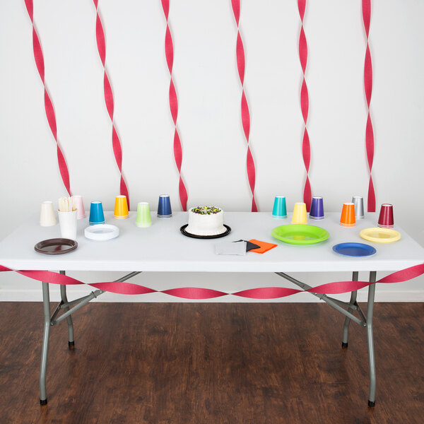 Burgundy Creative Converting streamers on a table with a white cake and cups.