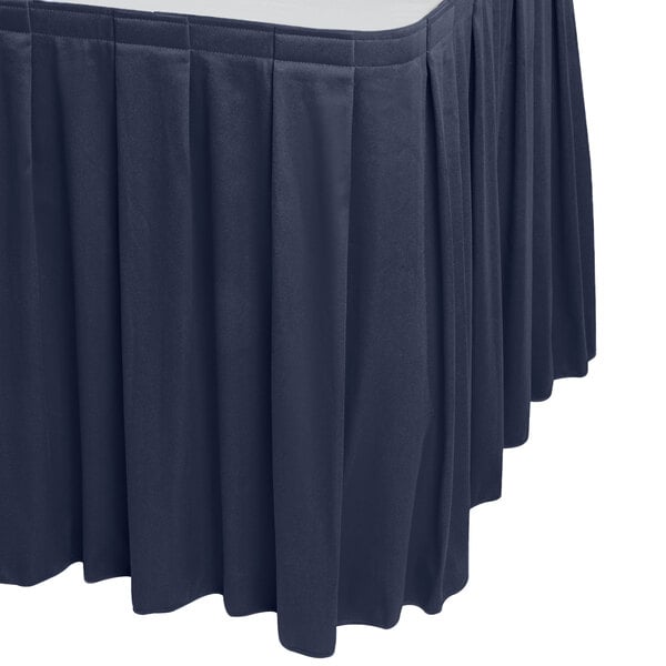 A navy blue Snap Drape table skirt with pleated edges on a table.