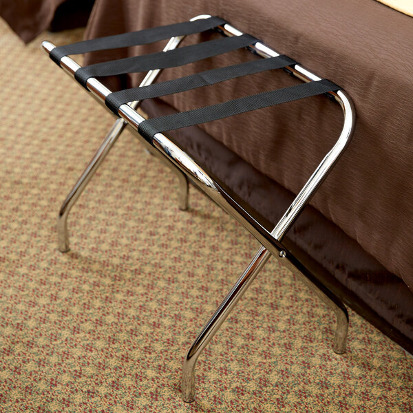 A CSL Chrome metal luggage rack with a suitcase on top of a bed.