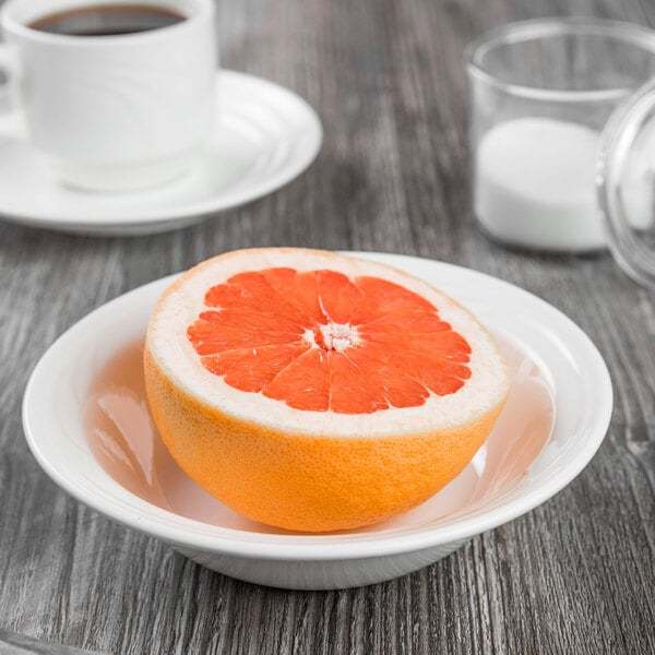 A Libbey white porcelain grapefruit bowl filled with half of a grapefruit on a table.