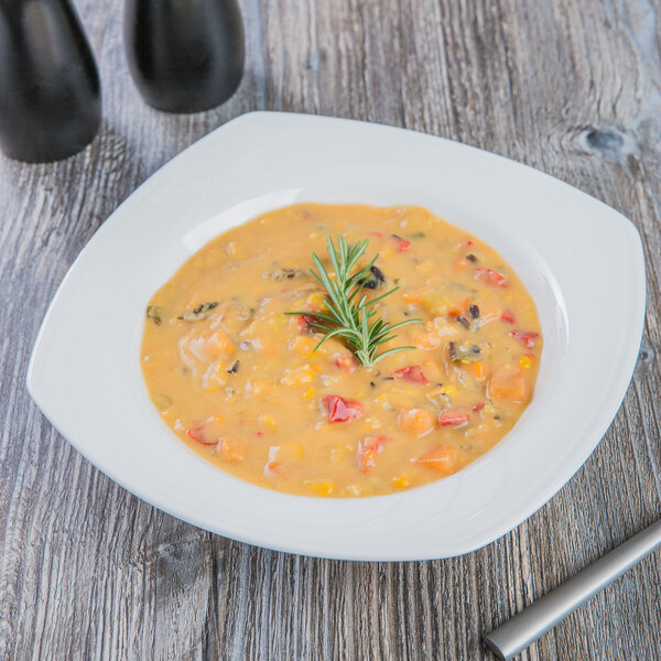 A bowl of white soup with a sprig of rosemary.