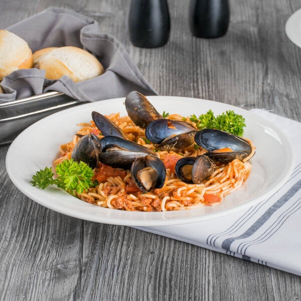 A Libbey Royal Rideau white porcelain pasta bowl filled with spaghetti, clams, and parsley.