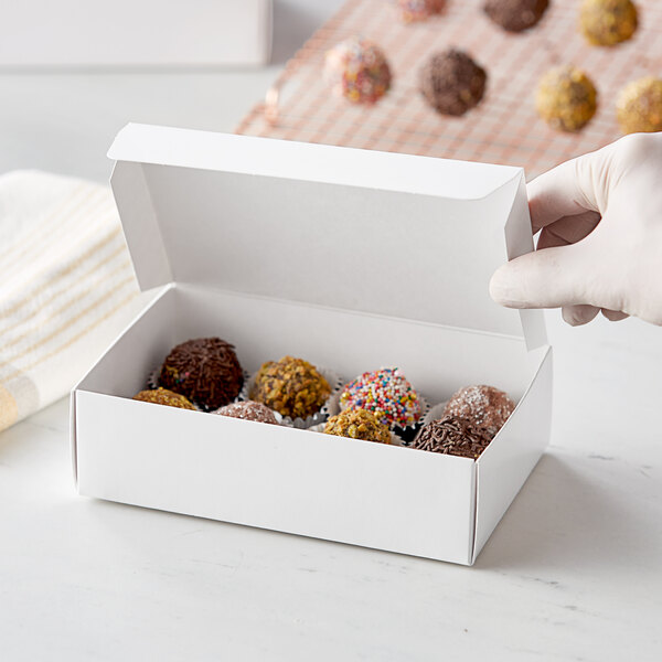 A hand holding a white box of chocolate.