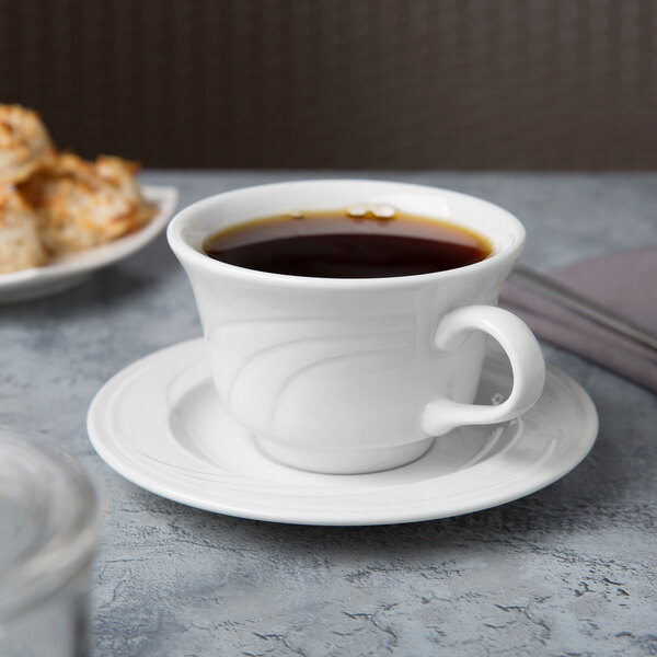 A cup of coffee on a Libbey Royal Rideau white porcelain tea saucer.