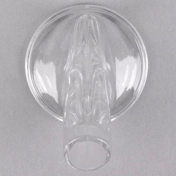 A clear plastic object with a round base, a handle, and a spout.