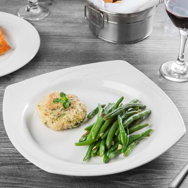 A Libbey white porcelain square bowl filled with food on a table.