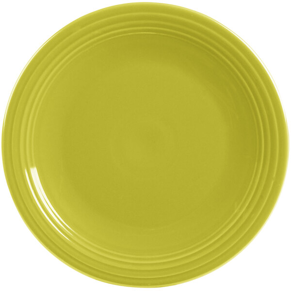 A close-up of a yellow Fiesta® Dinnerware round chop plate with a rim.