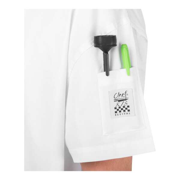 A white short sleeve garment with a small pocket on the sleeve holding a black tool and a green pen, featuring a label that reads 'Chef Revival.'