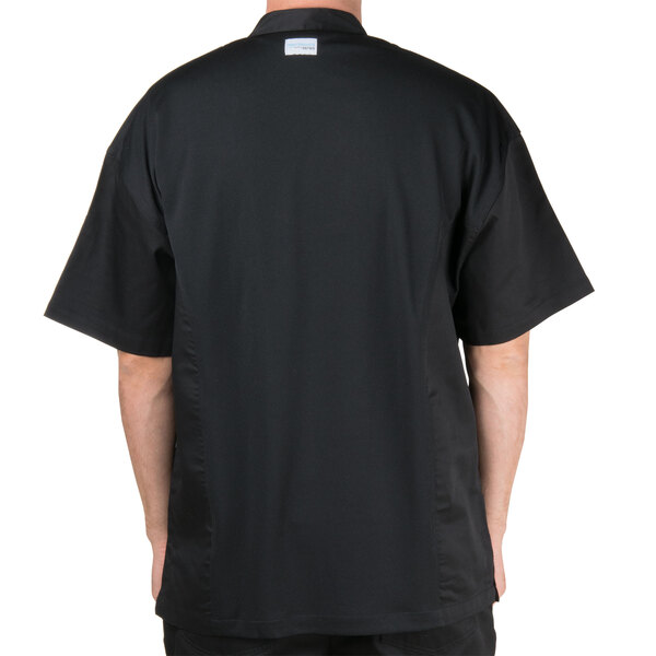 A man wearing a black Chef Revival short sleeve chef jacket with a mesh back.