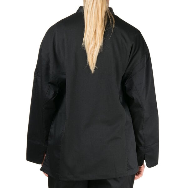 A woman wearing a black Chef Revival long sleeve chef jacket with mesh back.