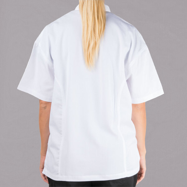 A woman wearing a white Chef Revival short sleeve chef jacket with mesh back.